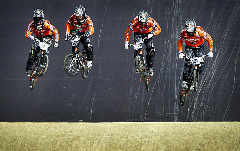 BMX'ers springen door de lucht tijdens een wedstrijd op de baan op Papendal.