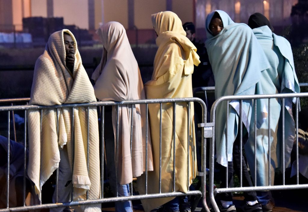 2016-10-26 05:57:57 TOPSHOT - Migrants wrapped in blankets queue for transportation by bus to reception centres across France, from the "Jungle" migrant camp in Calais, northern France, on October 26, 2016 as part of the full evacuation of the camp. Demolition crews continue to tear down the notorious "Jungle" migrant camp, one of the biggest in Europe where 6,000-8,000 people -- among them an estimated 1,300 children -- have been living in dire conditions. / AFP PHOTO / PHILIPPE HUGUEN